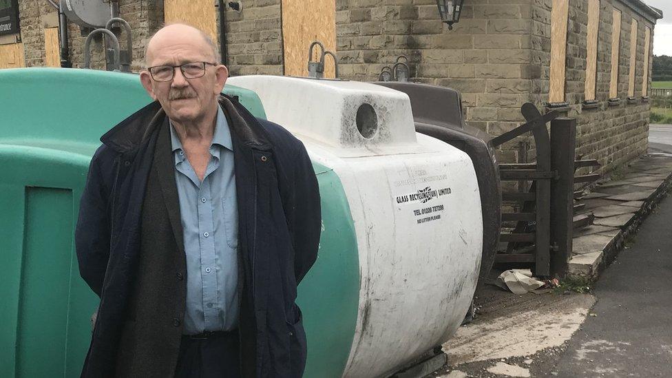 Conservative councillor Bill Armer standing in front of bottle banks