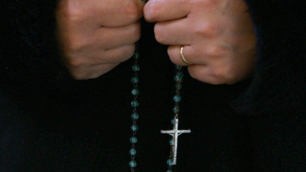 Woman praying with rosary beads