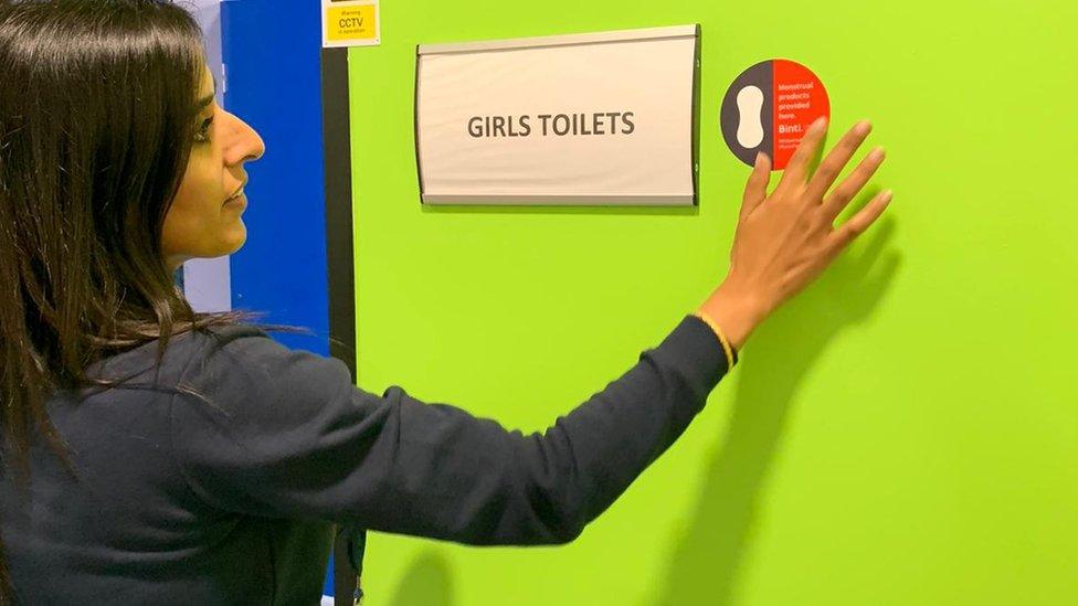 Teacher putting up sticker outside toilets