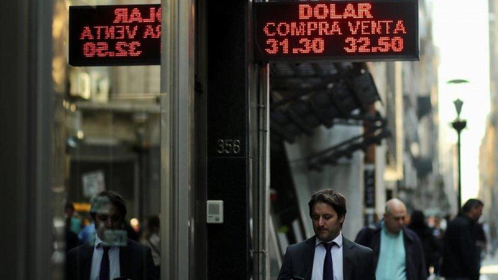 People walk past an electronic board showing currency exchange rates in Buenos Aires" financial district, Argentina August 29, 2018