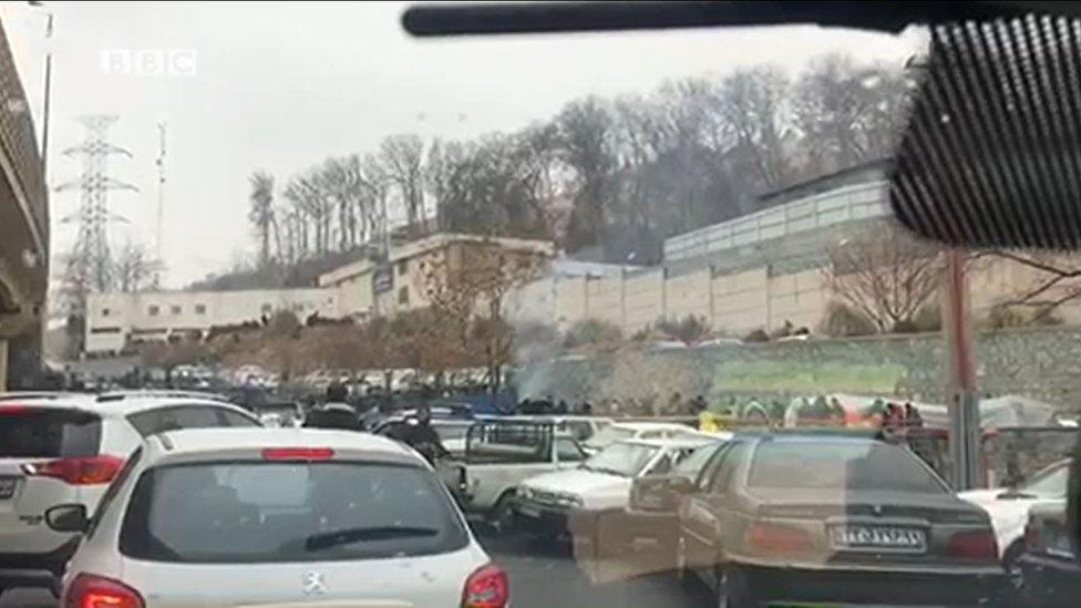 A screen grab shows exterior view of Evin Prison in Tehran with crowd gathered and some tents