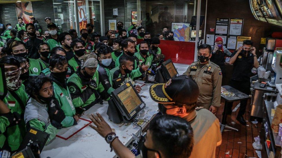 Food delivery riders queue up at a McDonalds outlet in Bogor on June 9, 2021, to buy the new BTS-meal deal for hungry fans in the K-Pop mad country, causing more than a dozen McDonald's outlets to temporarily shuttered over virus fears