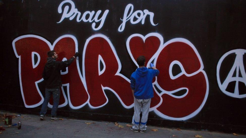 Two men paint a mural in tribute to the victims of the Paris attacks, in Paris, 14 November 2015