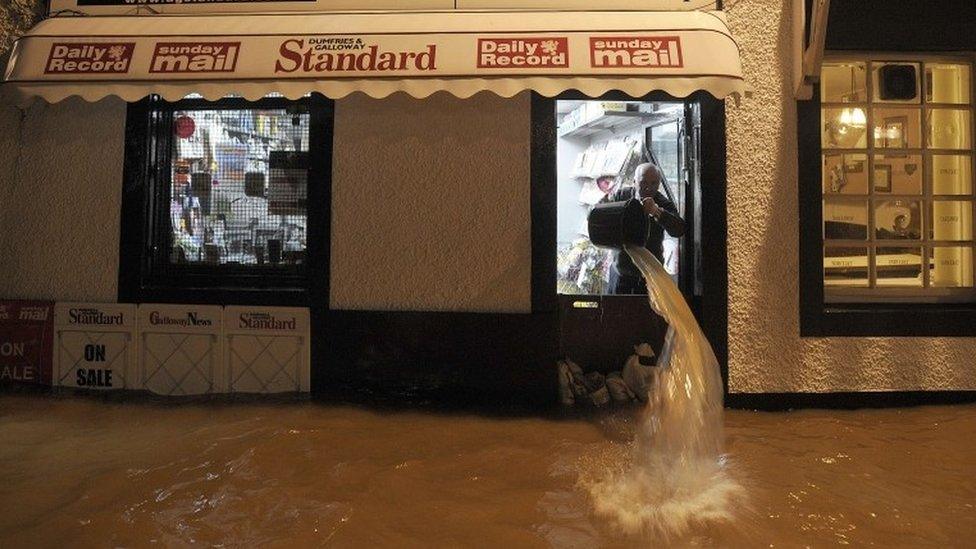 Man bailing floodwater from shop