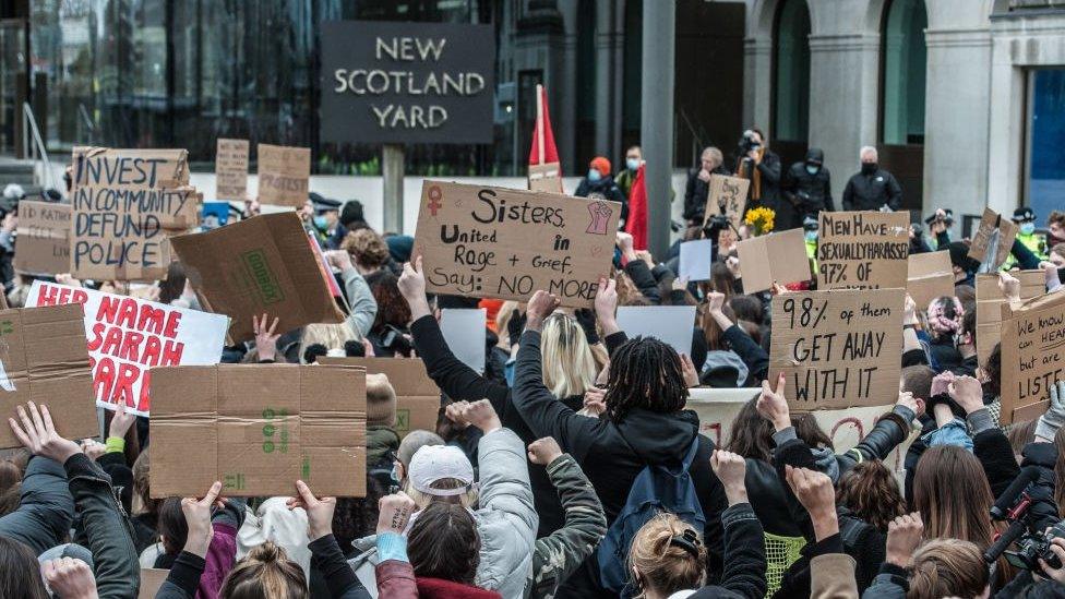 Protesters hold signs outside New Scotland Yard