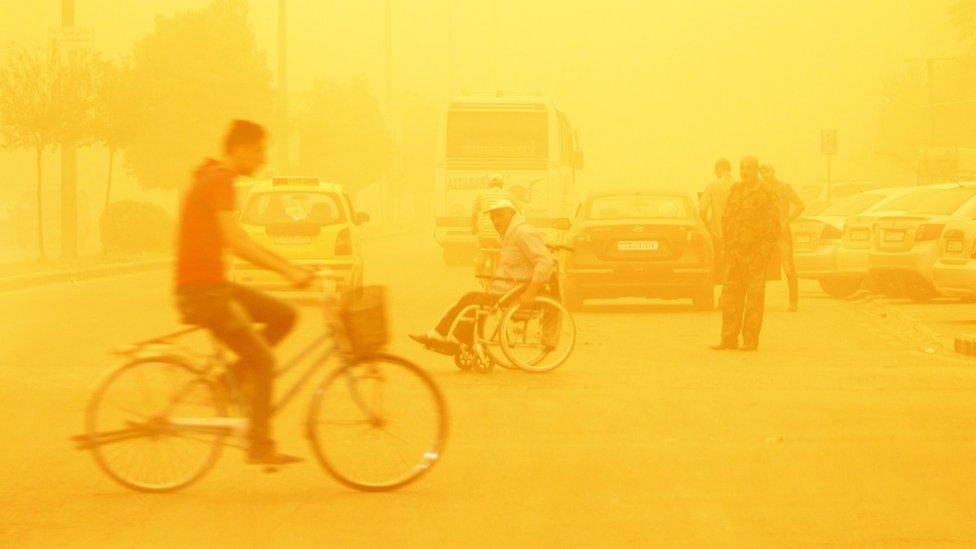 A man rides a bicycle through a sandstorm in Homs, Syria September 7, 2015