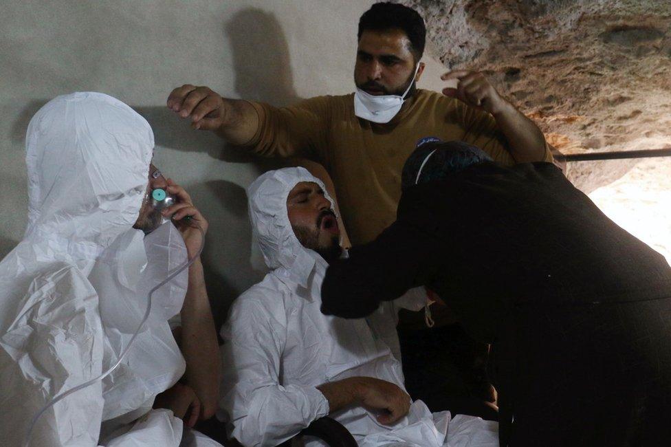 A man breathes through an oxygen mask as another one receives treatment, after what rescue workers described as a suspected gas attack