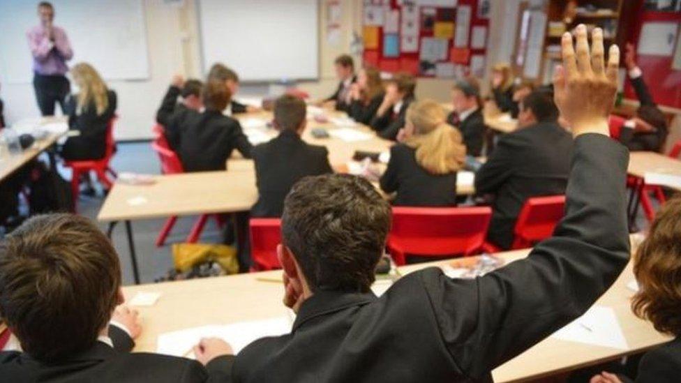 A boy raises his hand in class