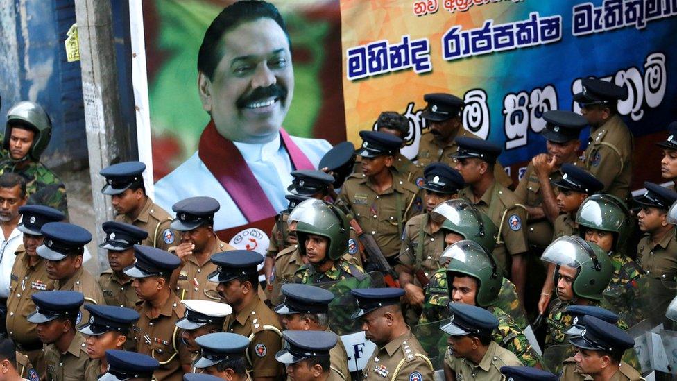 Members of Sri Lanka's Special Task Force and police officers stand alongside a poster of newly-appointed Prime Minister Mahinda Rajapaksa, 28 October 2018