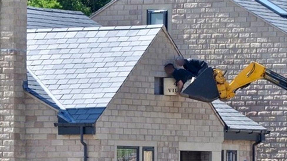 Workers standing in the bucket of a digger at The Villas