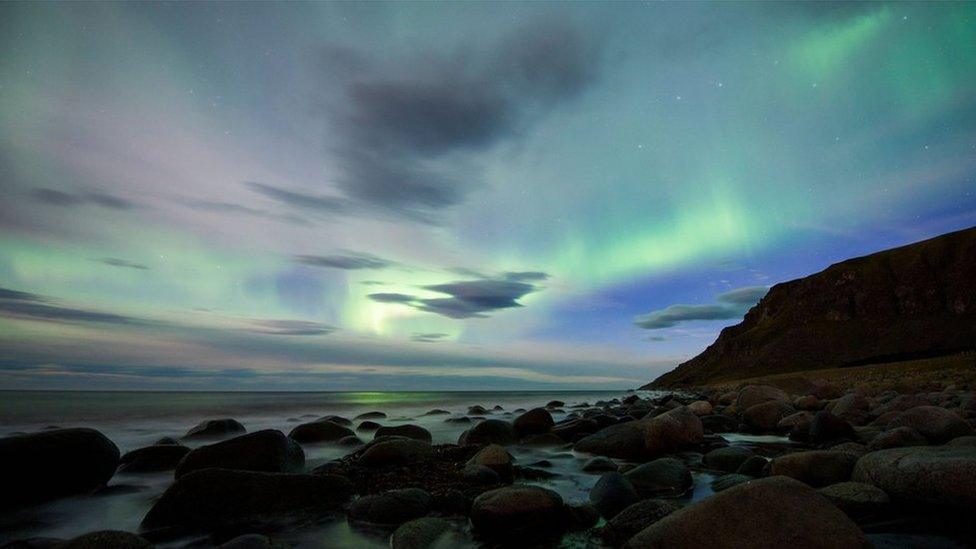 Northern lights over mountain and rock