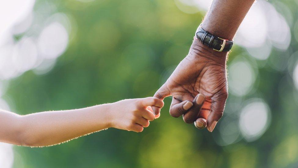 Child holding adult's hand