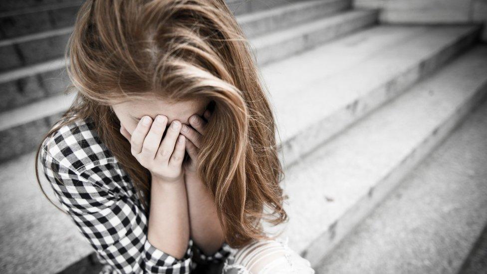 Teenage girl with head in hands