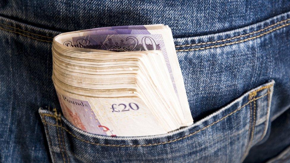 Bundle of cash in a jeans pocket