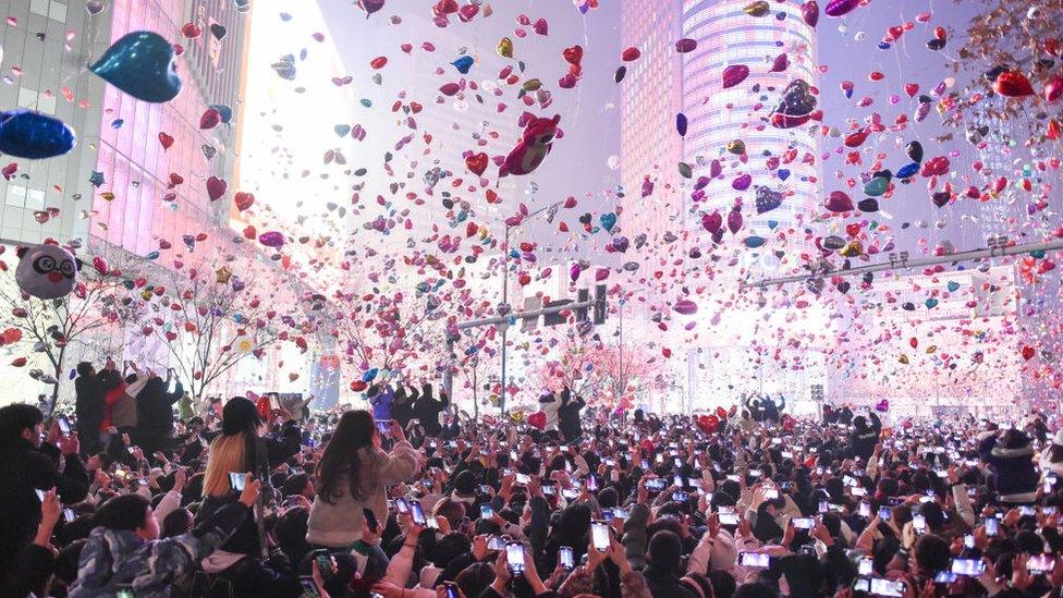 Balloons - some heart shaped and others in the shape of animals - float above people's heads in Xinjiekou in Nanjing, China