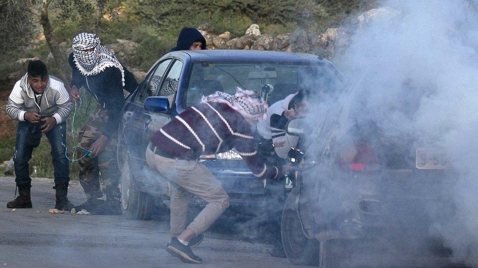 Palestinian youths take cover amid a cloud of tear gas, during a clash with Israeli forces near Beita, in the occupied West Bank (11 March 2020)