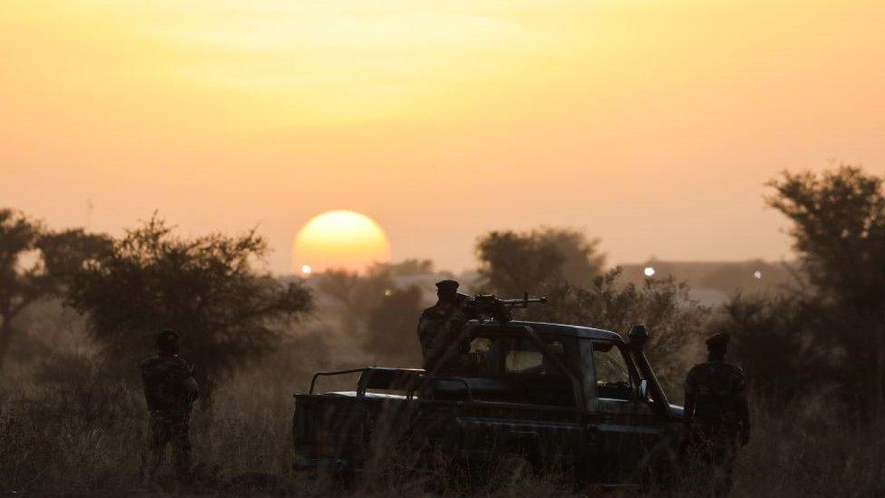 Soldiers stand guard at sunset as France's President and Niger's President Mahamadou Issoufou (unseen) take part in a military ceremony at the Martyr Quarter