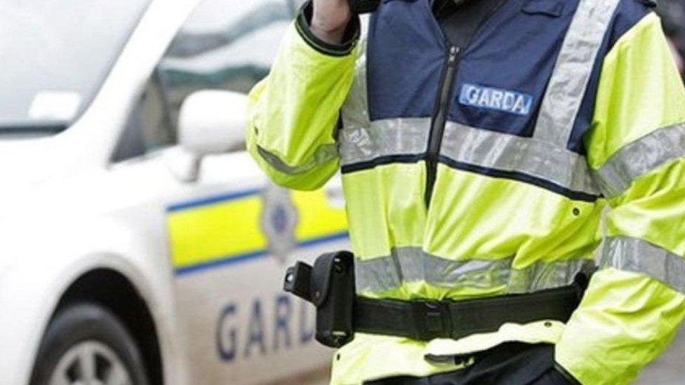 A gardaí standing beside a patrol car