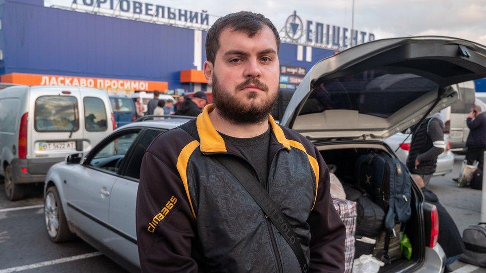 Anton Osenev standing next to a car boot that contains luggage