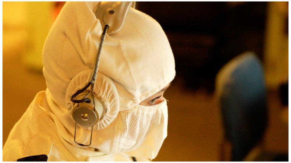 A female sailor is seen wearing headphones over her protective gear