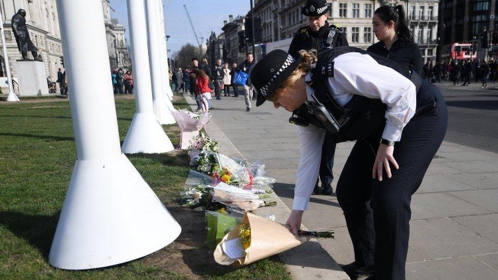 A London Metropolitan Police female officer lays floral tributes outside parliament in London