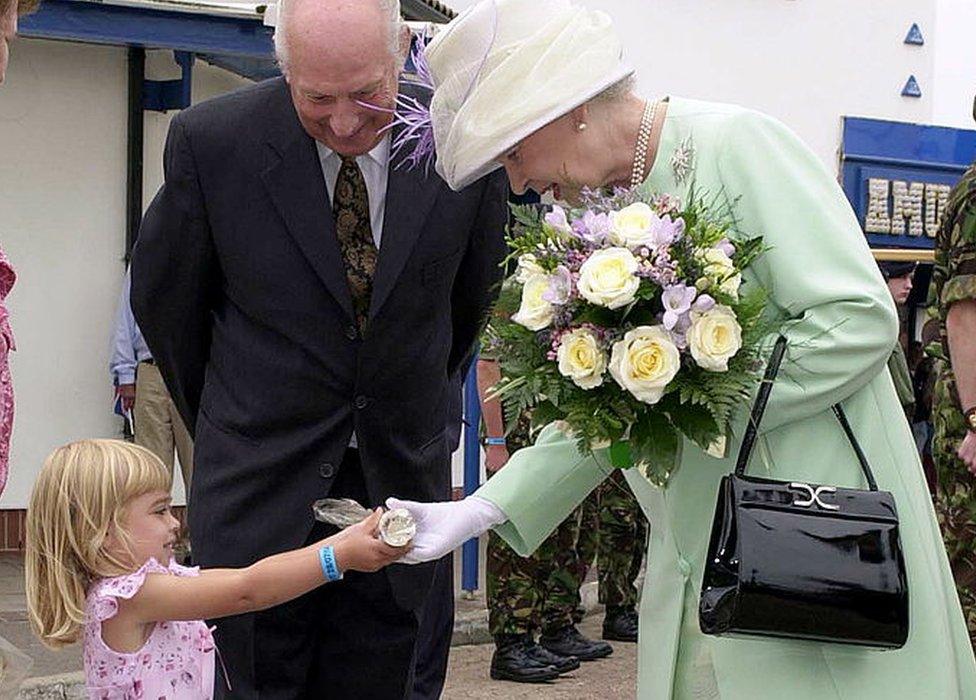 The Queen being presented with a stick of rock