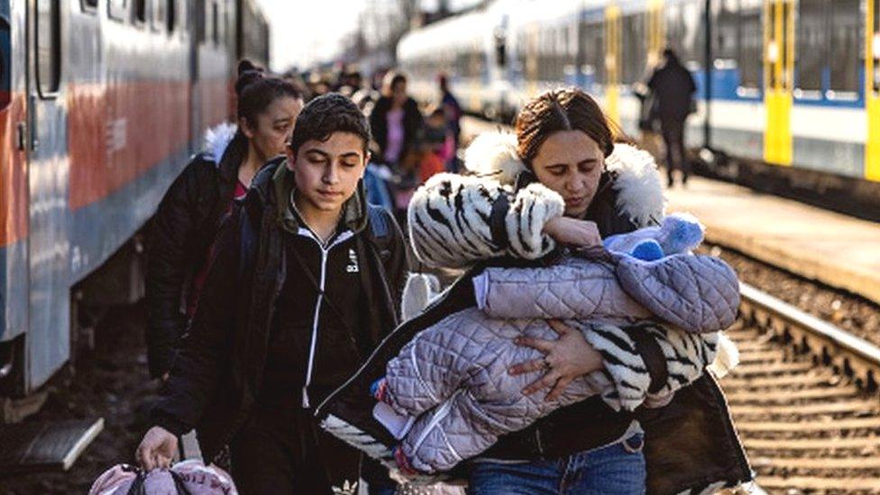 A family holding a baby walking next to a train