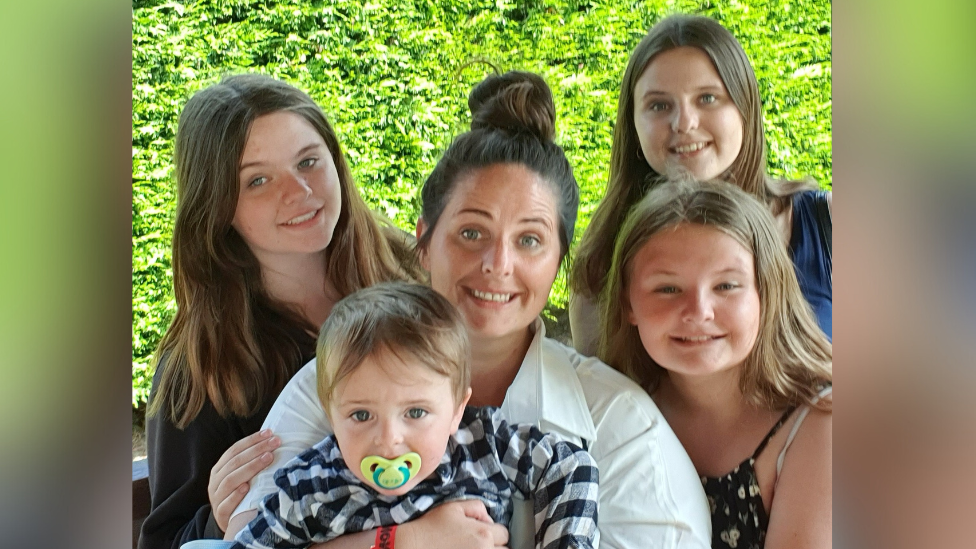 Laura-Jane Seaman smiles at the camera surrounded by her four young children