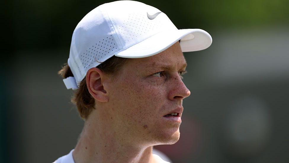 Jannik Sinner wearing a white baseball cap at Wimbledon