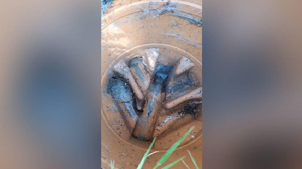A large sewage pipe with smaller pipes leading off from it. They are covered in brown liquid.