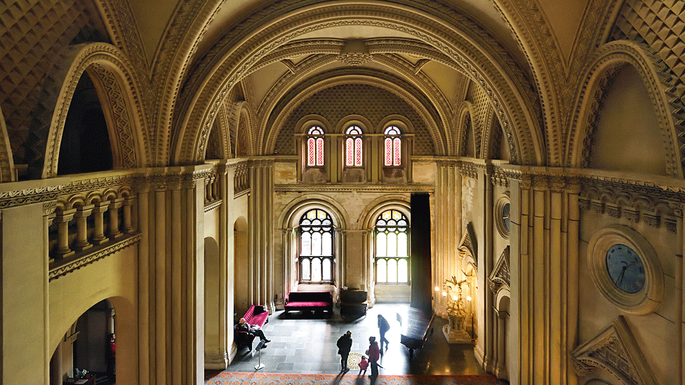 Moody lighting looking top down from one end of the castle's Grand Hall towards the arched windows at the opposite end