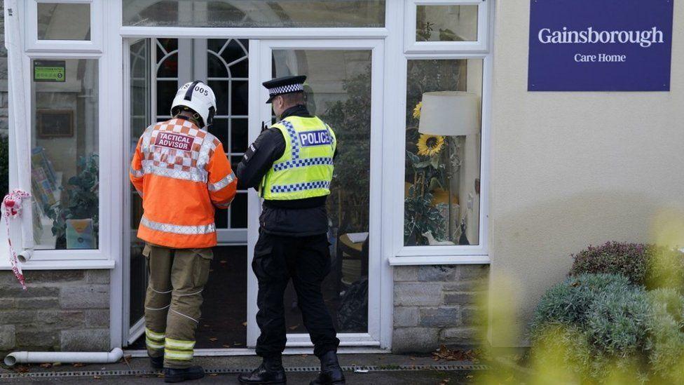 White glazed entrance with backs of police officer and fire fighter standing in the doorway