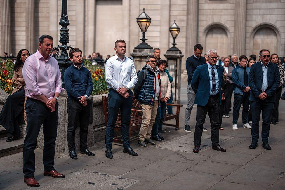 People stand outside the Bank of England as they observe a two minute silence to mark the 80th anniversary of VE Day on May 8, 2025 in London, England.