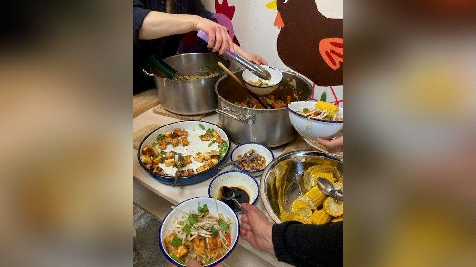 Food being served from silver pan into bowls