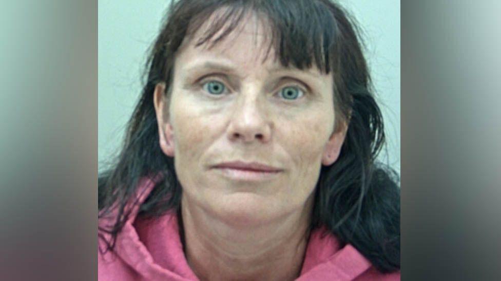 Pamela Urvoy's mugshot. She has long dark hair, green eyes and is wearing a pink hoodie
