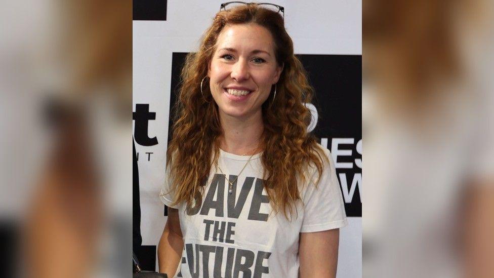 Amelia Twine, who has long light brown hair and is wearing a t-shirt that says "save the future" on it.