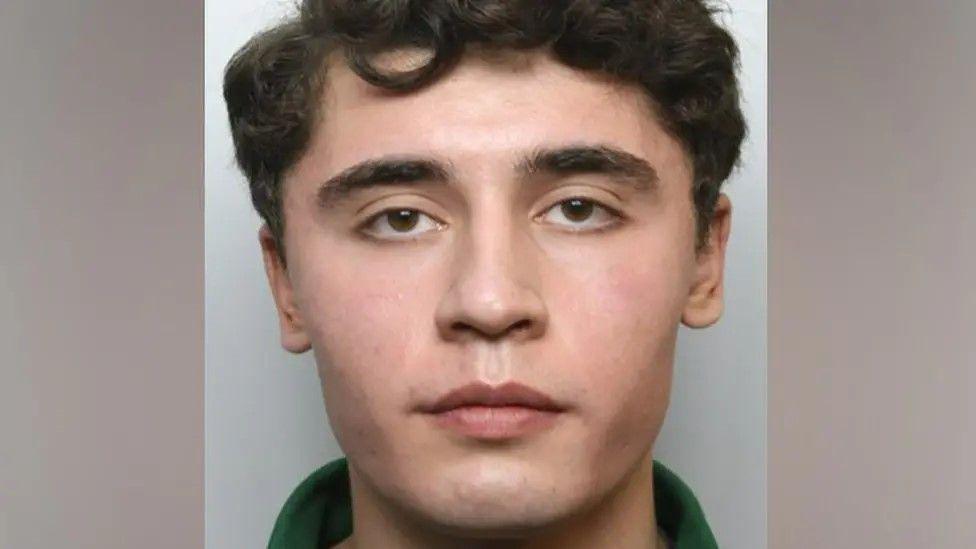 A police mugshot of Daniel Khalife, a man with dark hair and a green collar