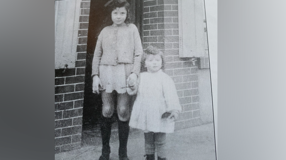 Arlette Gondree holds her older sister's hand outside the cafe Gondree