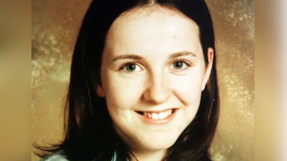 A girl with long brown hair smiling at the camera