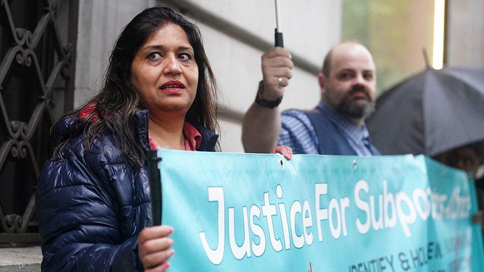 Sub-postmaster Seema Misra protesting with a blue banner