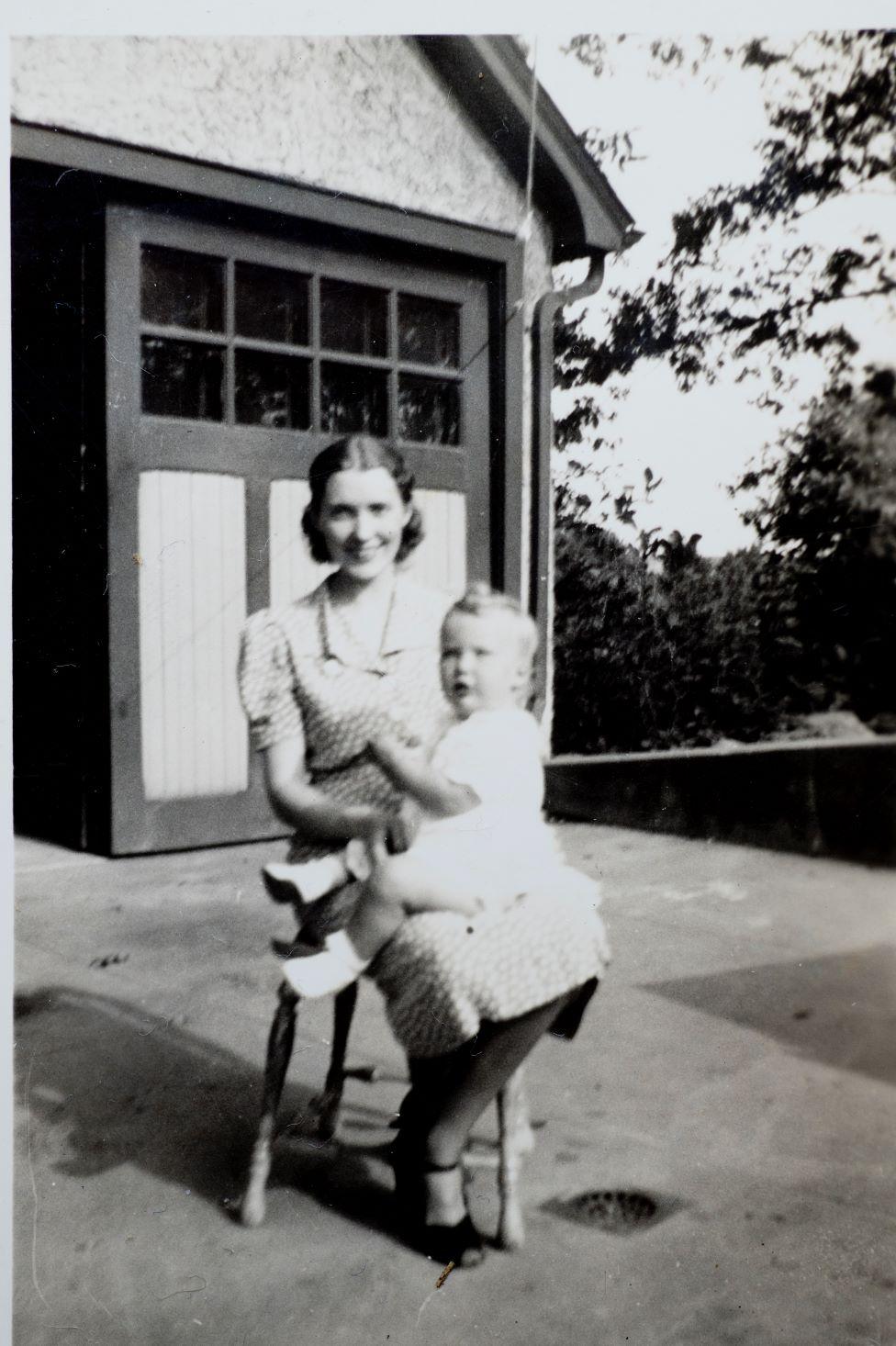 Trump's mother, Mary Anne MacLeod, is facing the camera as she sits with baby Maryanne, Donald's sister, in her lap. They are outside in front of double doors and it's 1938