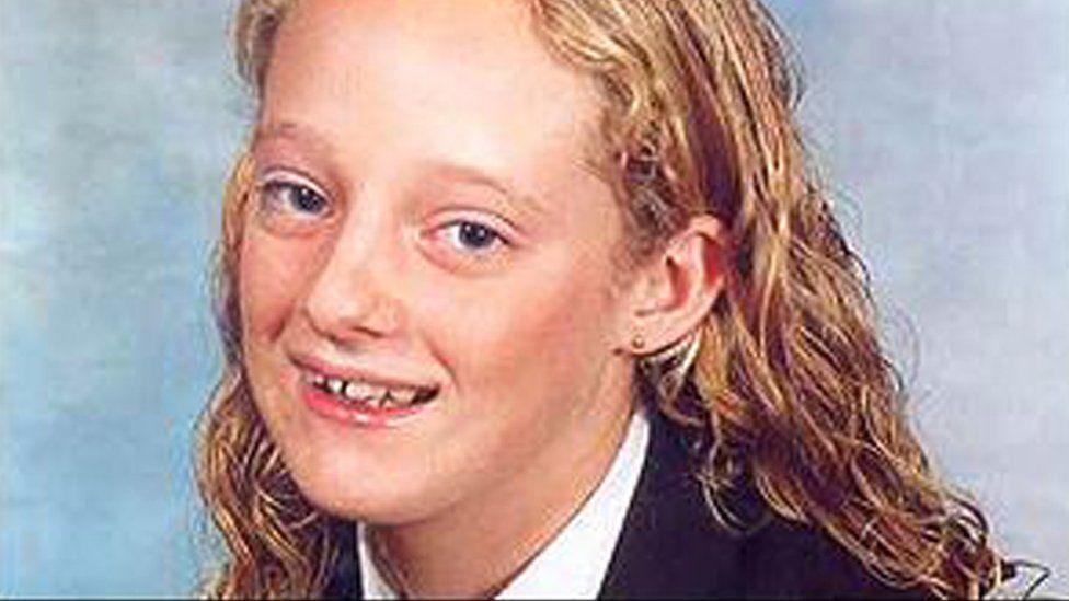 A school picture of Danielle Jones, who has wavy blonde hair and is smiling. She has blue eyes and is wearing a navy blazer with a white shirt