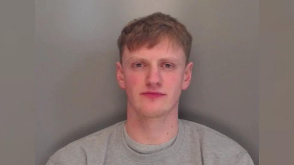 Matthew Hindhaugh with short brown hair looking at camera wearing a grey jumper.