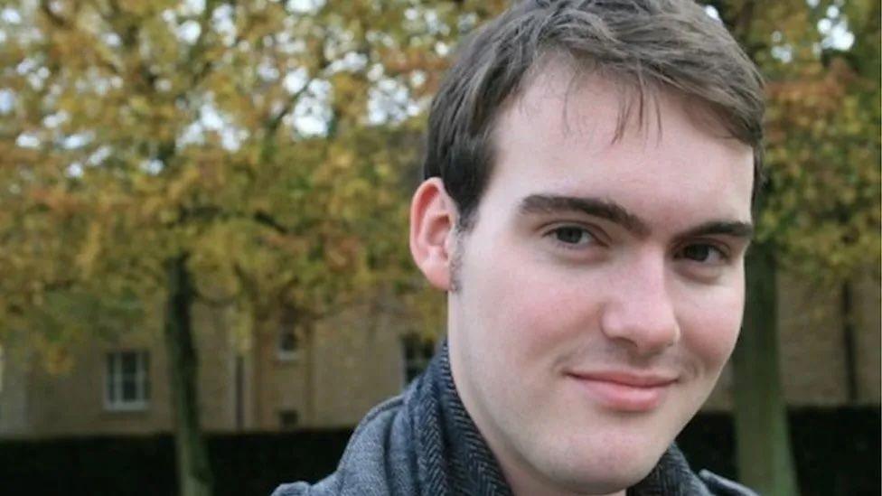 Martin Higson with dark hair, smiling. with trees in the background