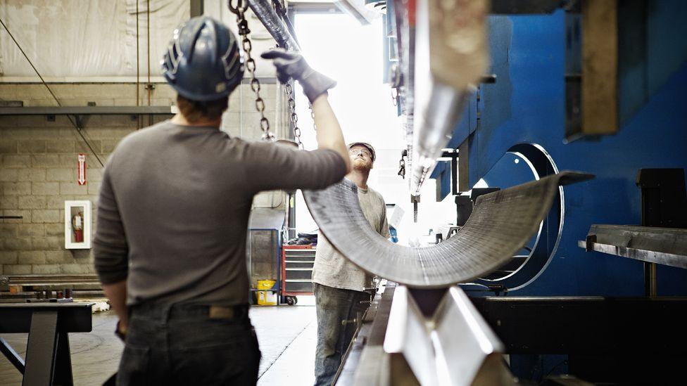 Steel workers operate machinery