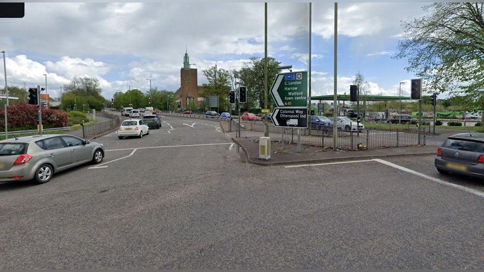 Road coming off roundabout with cars and road signs