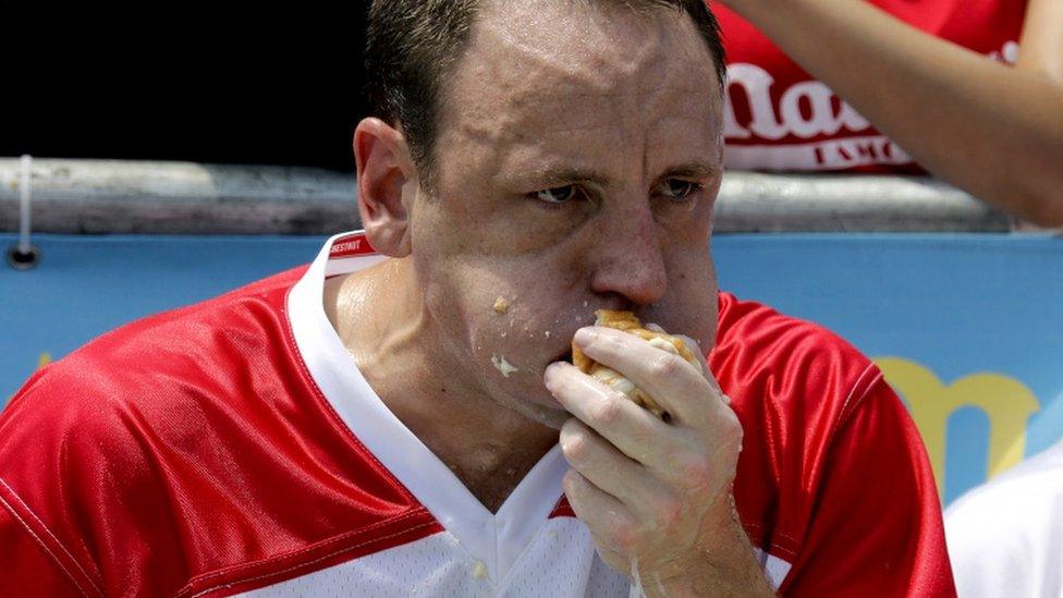 Joey Chestnut strains to fit hot dog in mouth in close-up photograph