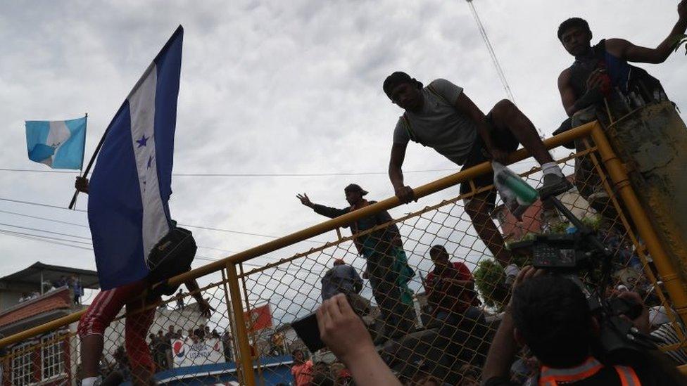 Members of the migrant caravan climb over a gate separating Guatemala from Mexico on 19 October 2018 in Ciudad Tecun Uman, Guatemala.