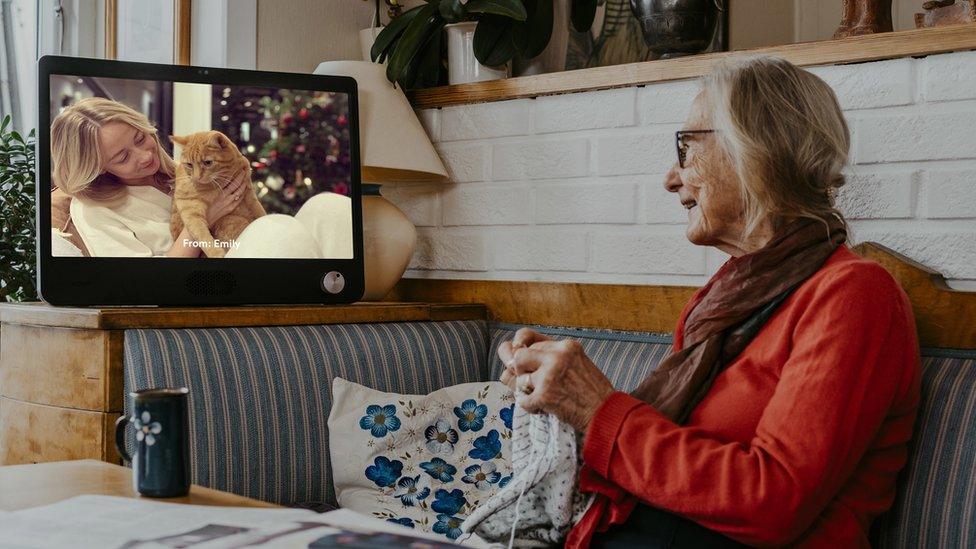 An elderly woman using a Komp video call machine