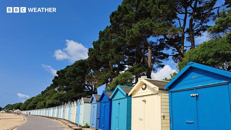 Blue skies above colourful beach huts in Mudeford, Dorset, on 26 June 2023